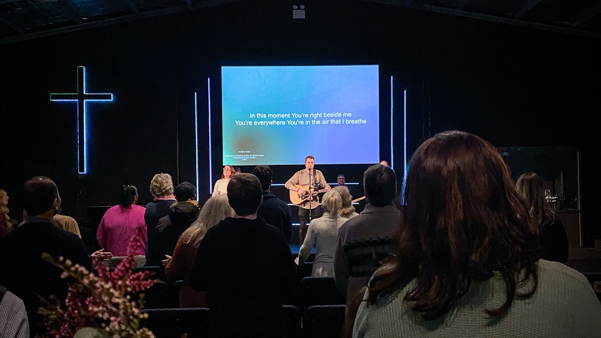 Inside Colour City Church during worship, singer and guitarist on stage.